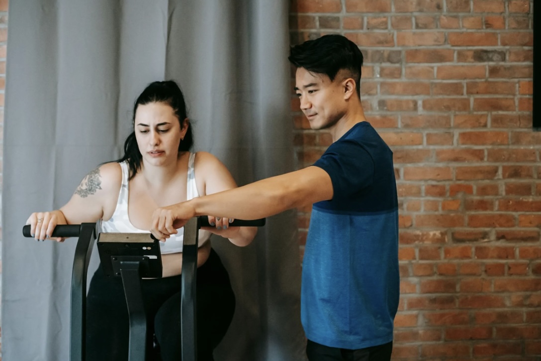 Trainer guiding woman on rowing machine