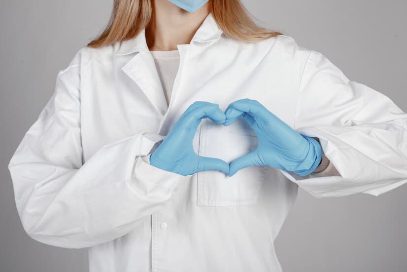 Doctor in a Mask Shows a Heart with Her Hands