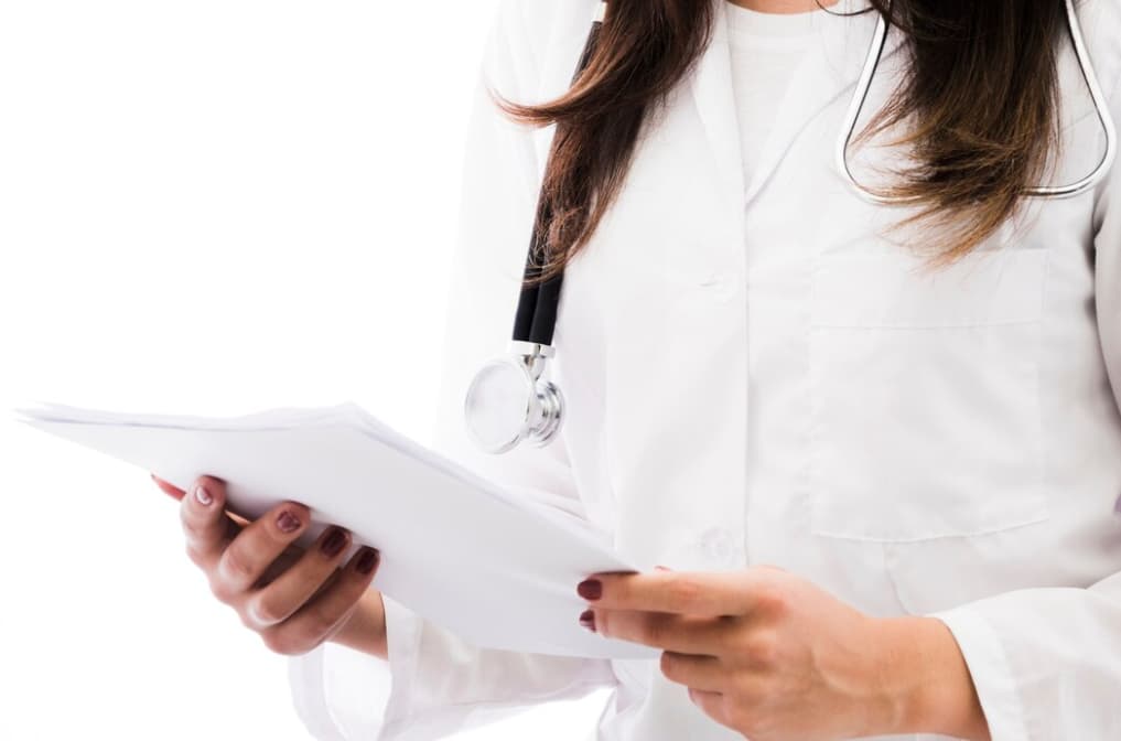 A doctor reading a document with a stethoscope around the neck