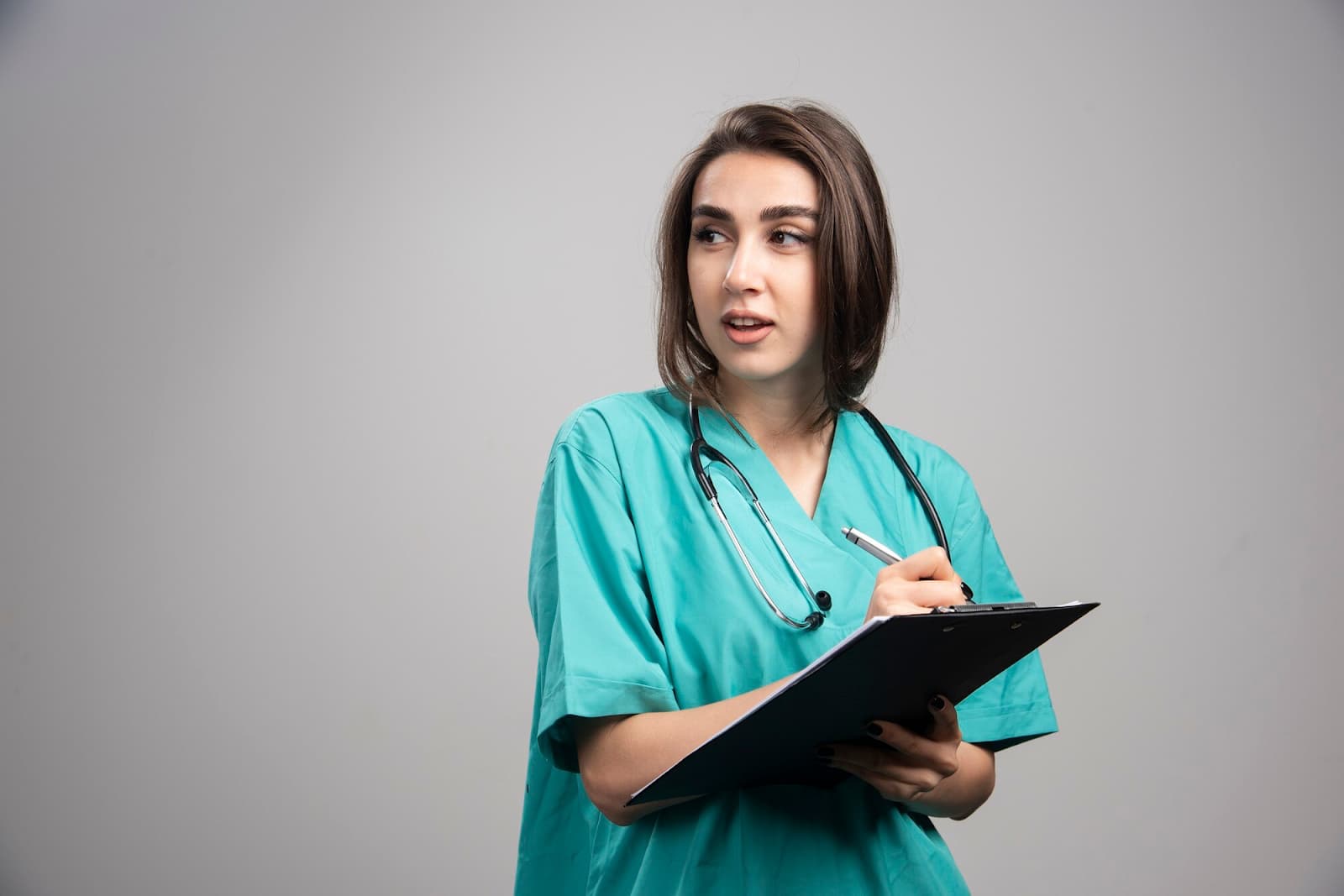 Female doctor with stethoscope writing on clipboard