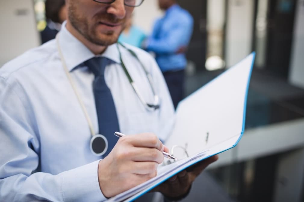 A doctor in a blue shirt reviews a medical chart