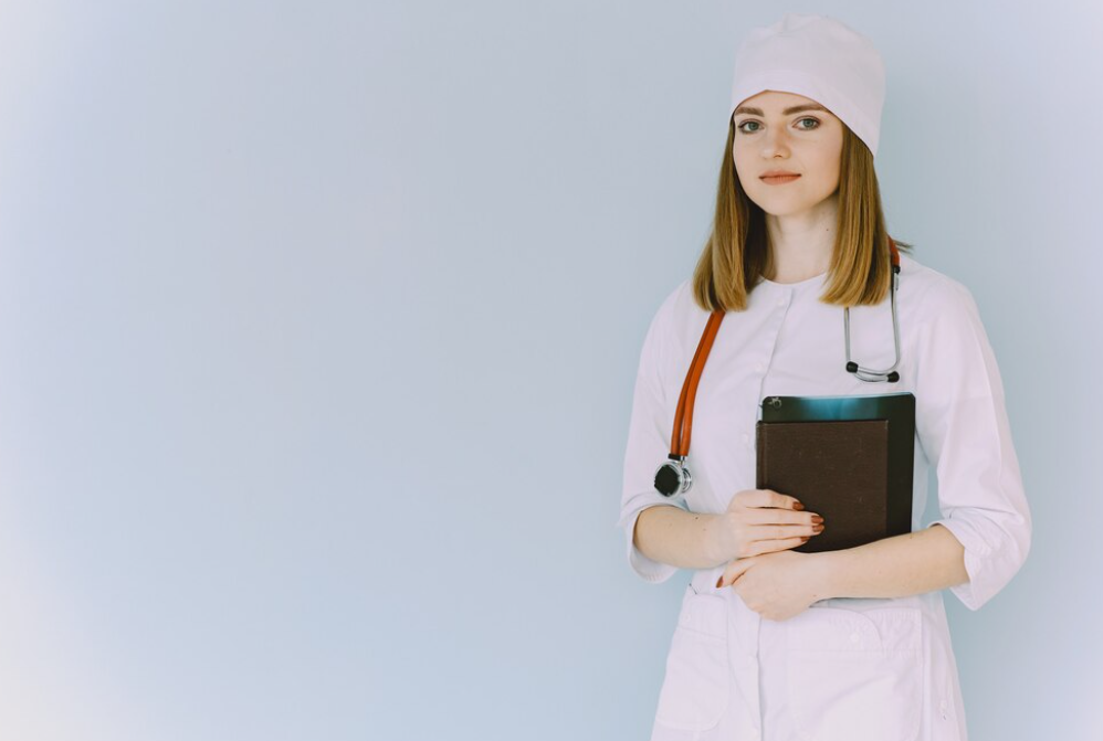 A young female doctor holding a clipboard against a blue background