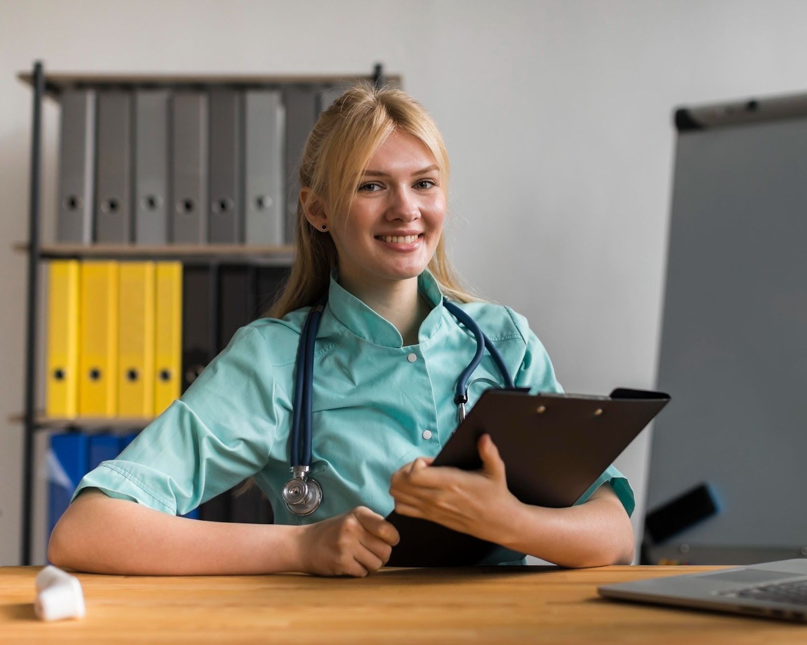Smiley female nurse in the office with notepad and stethoscope
